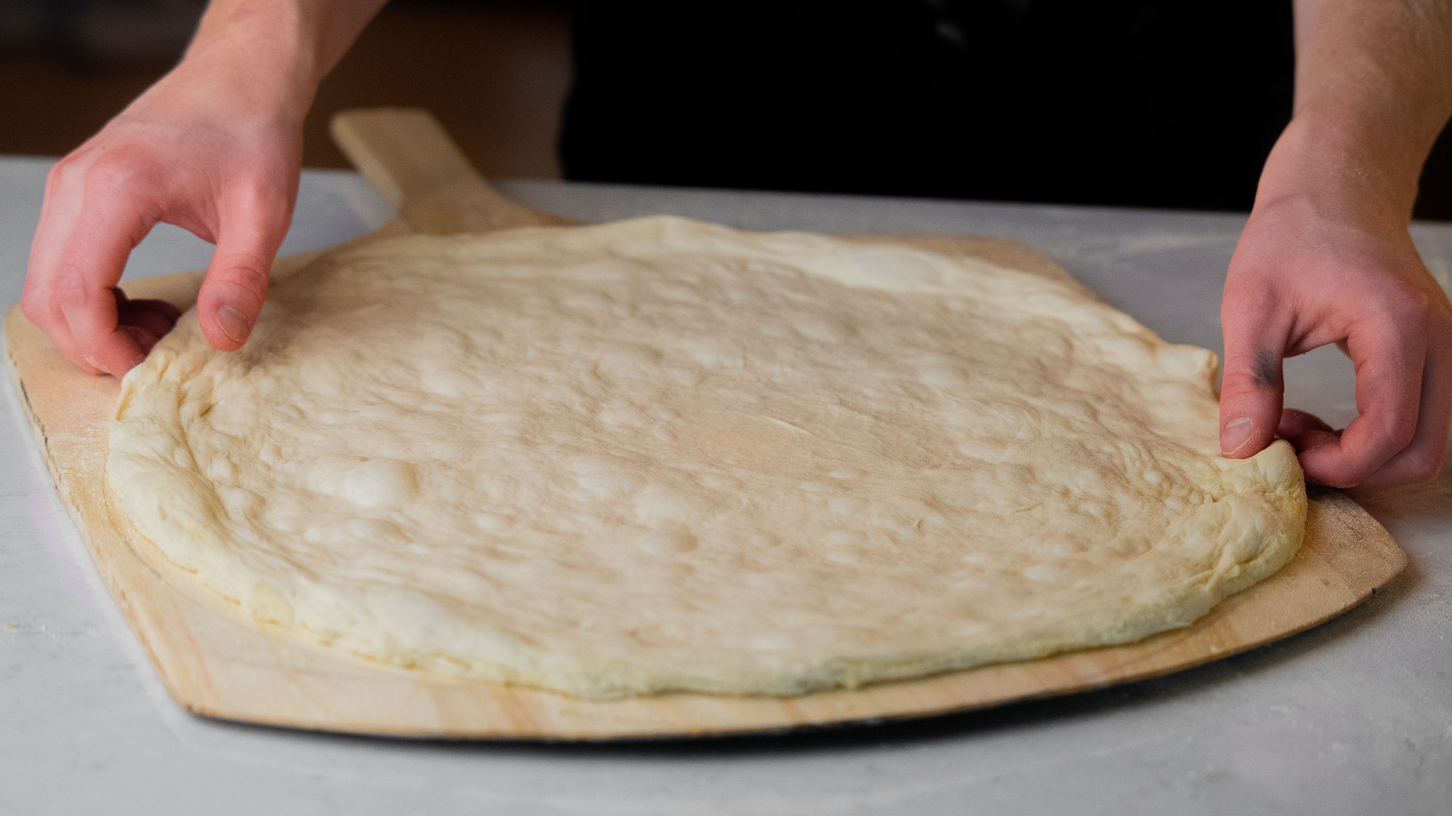 Perfectly proofed airy pizza dough on peel